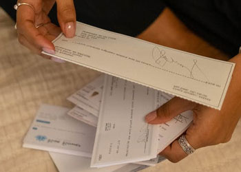 A woman holding out envelopes and letters