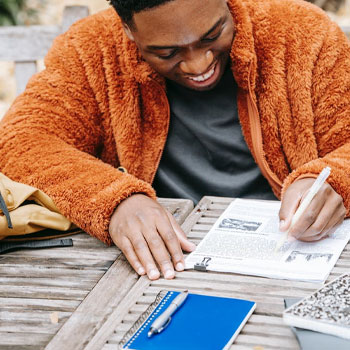 A man studying on a table outdoors for GED essasy