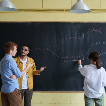 Students discussing beside a black board