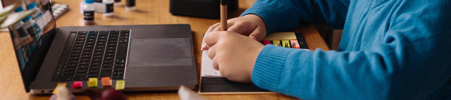 A student writing a note during online class