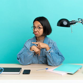 female student pointing at her wrist seated on desk