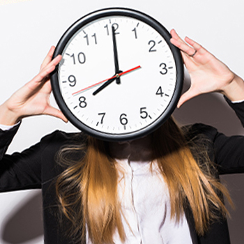 A woman covering her face with a clock symbolizing time management