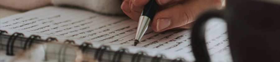 A student writing a long sentence on a notebook