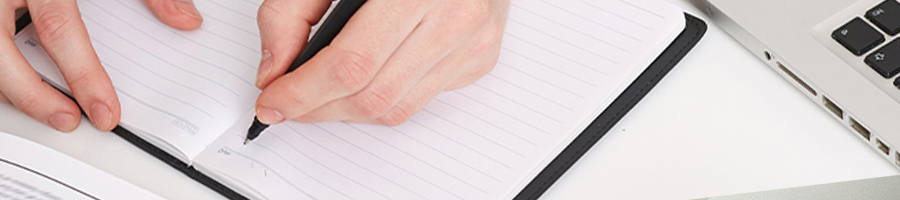 Top view of someone writing on a notebook