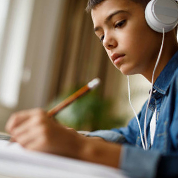 A young mean wearing headphones and holding a pencil