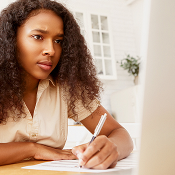 A woman taking down notes during an online class