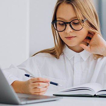 A woman in glasses with an open book and holding a pen