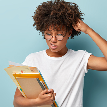 A woman looking at her files while scratching her head