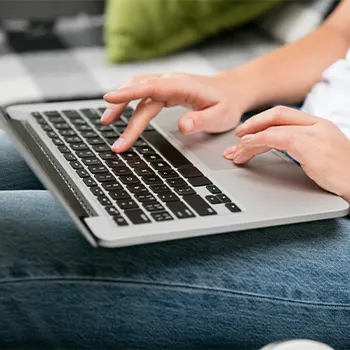 Close up image of a person's hand while typing on laptop