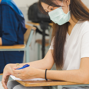 A woman with facemask answering an exam