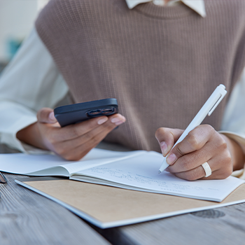 person studying using phone and notebook