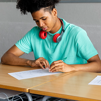 student sitting on his desk with a paper and pen