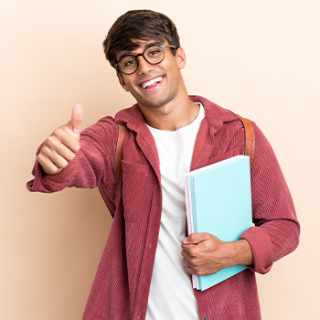 male student holding up a thumbs up and books