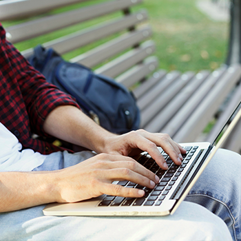 man typing on laptop outdoors